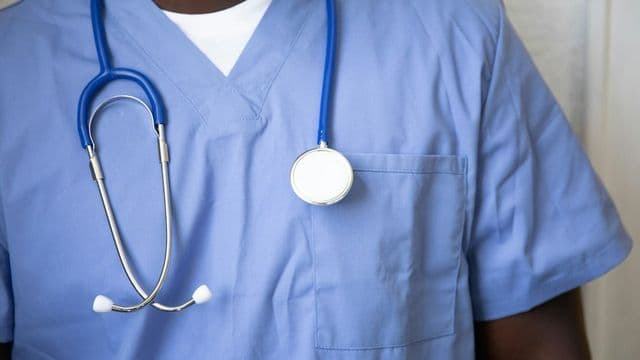 Enfermeiro de uniforme azul com estetoscópio ao pescoço, pronto para o atendimento em oncologia