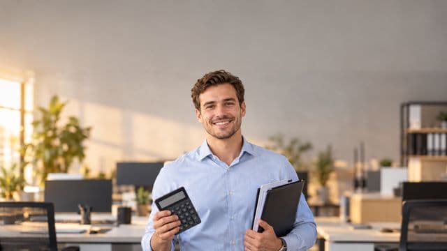 Contador sorrindo, com camisa social azul-clara, segurando uma calculadora e uma pasta de documentos, em um escritório contábil moderno