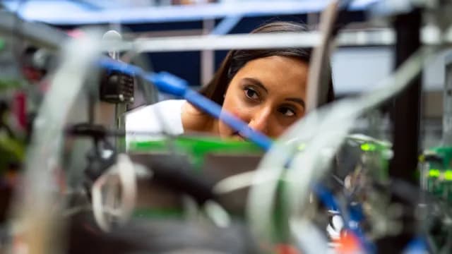 Engenheira de computação examinando de perto uma placa eletrônica no laboratório