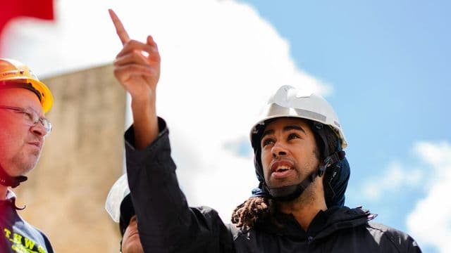 Engenheiro com capacete apontando e liderando equipe em obra, representando a transição para gestão em engenharia