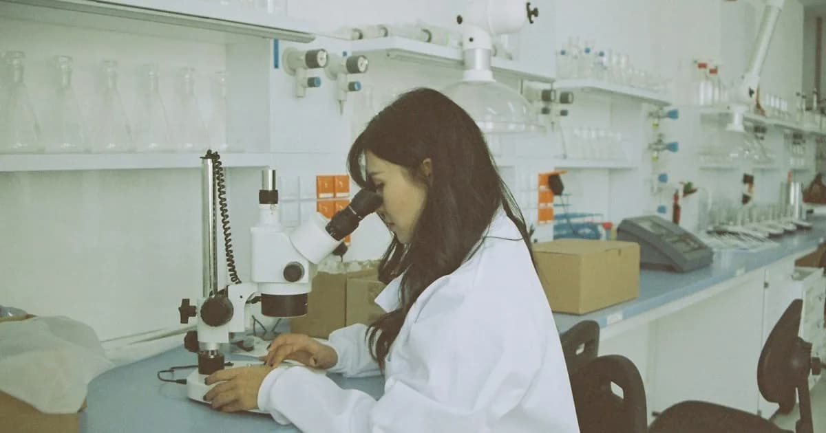 Profissional de laboratório analisando amostra em microscópio, área de antropologia forense