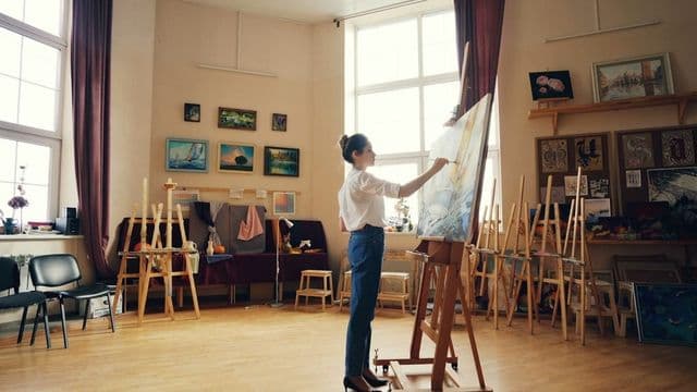 Arte-educadora pintando em ateliê, representando a profissão de arte-educador