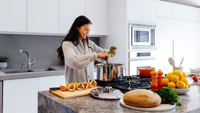 Mulher preparando refeição saudável com vegetais e frutas frescas, ilustrando a nutrição funcional