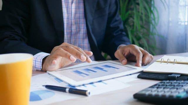 Profissional analisa relatórios financeiros em tablet, simbolizando o trabalho de contabilidade pública e controle da Lei de Responsabilidade Fiscal