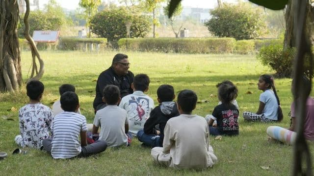 Professor conduzindo atividade de educação ambiental ao ar livre com um grupo de crianças