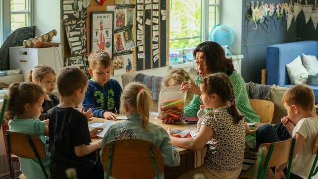 Professora distribui lápis de cor para turma de crianças em aula de Arte