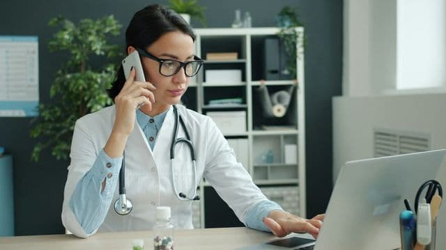 Enfermeira auditora analisando documentos e tela de computador em escritorio