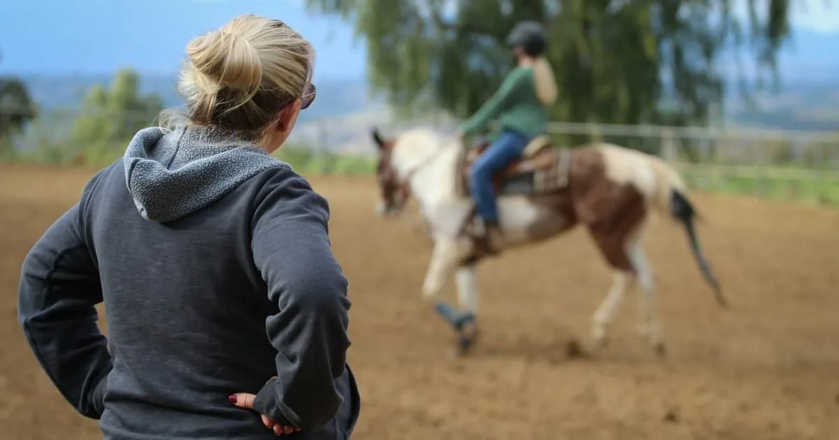 Instrutora acompanhando sessão de equoterapia com cavalo ao ar livre