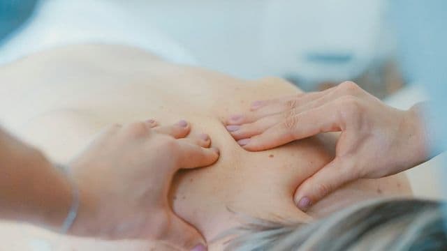 Profissional de estética corporal realizando tratamento nas costas de uma cliente em clínica de estética