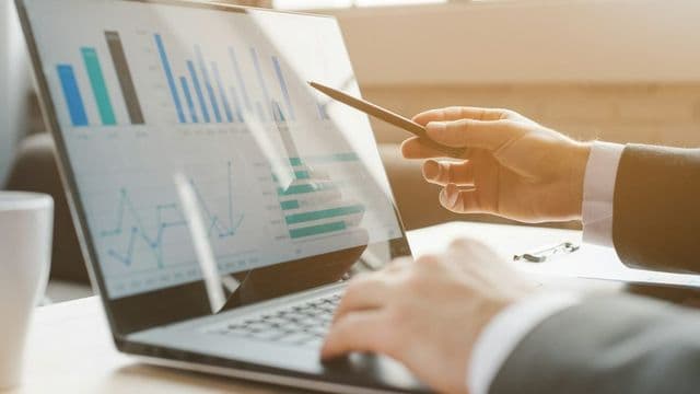 Gestor de marketing digital analisando gráficos de campanha em um laptop