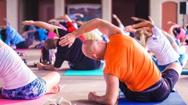 Grupo de pessoas em sessao guiada de alongamento, representando um programa de ginastica laboral