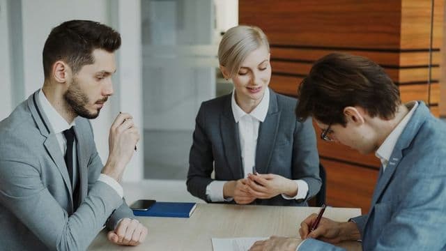 Equipe de profissionais revisando documento de planejamento em reuniao de gestao publica