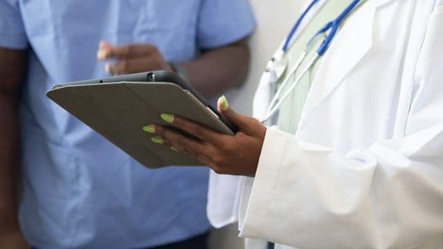 Equipe de profissionais de saúde consulta prontuário eletrônico em tablet durante o planejamento dos programas de saúde na unidade básica