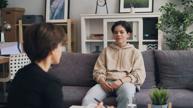 Psicólogo conversando com adolescente em sessão de psicoterapia em consultório