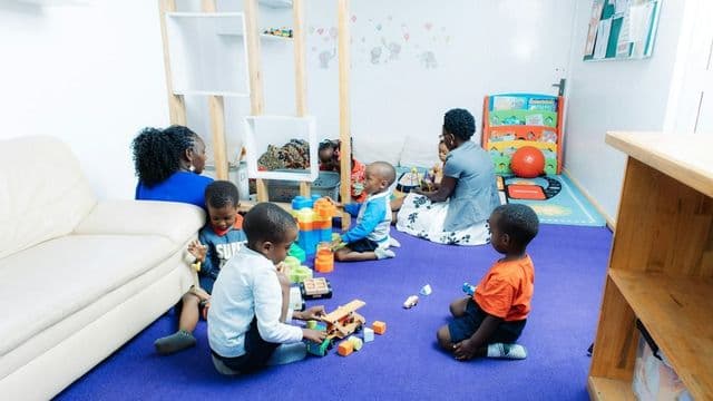 Educadora e criancas brincando com blocos de montar em sala de estimulacao psicomotora