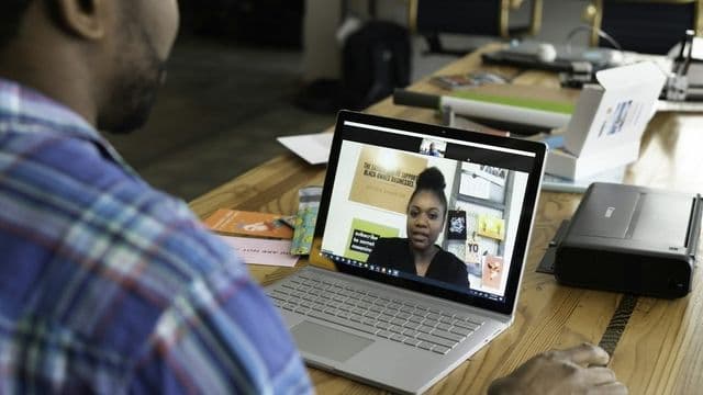 Estudante em videochamada com tutora EAD que conduz a aula na tela do notebook